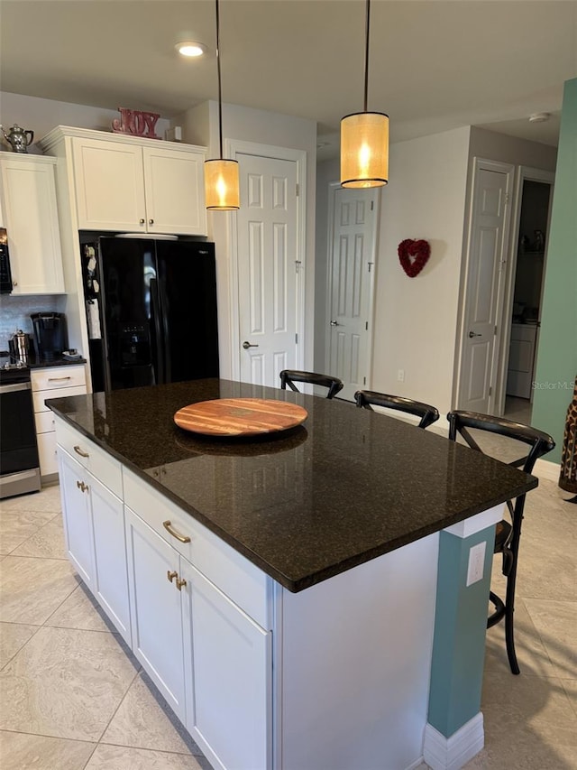 kitchen featuring white cabinetry, hanging light fixtures, stainless steel range with electric cooktop, and black fridge