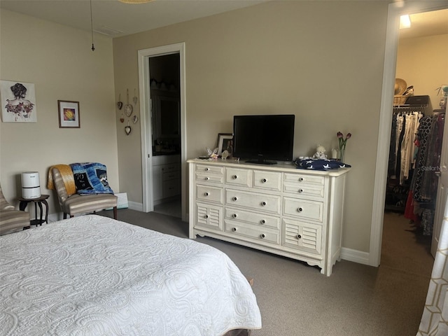 bedroom featuring dark carpet, a spacious closet, a closet, and ensuite bathroom