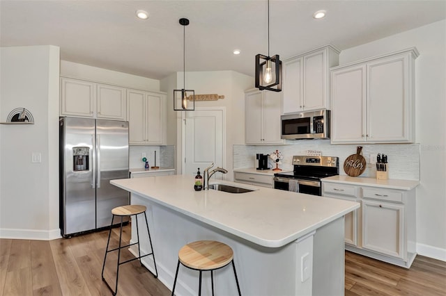 kitchen with sink, white cabinetry, appliances with stainless steel finishes, and an island with sink