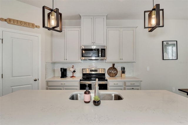 kitchen with decorative light fixtures, white cabinetry, and appliances with stainless steel finishes