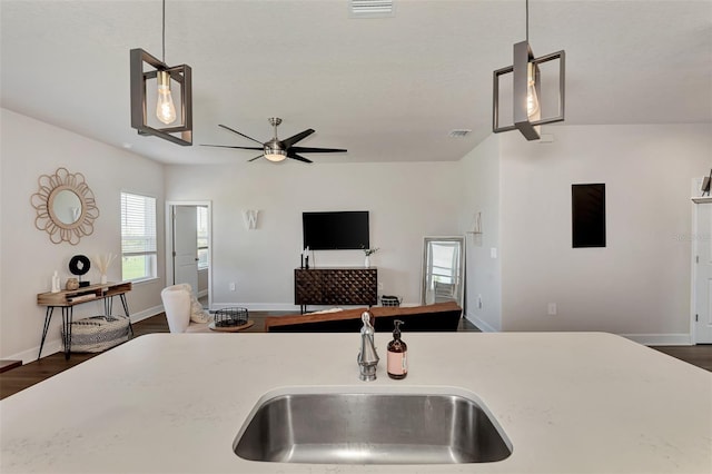 kitchen with dark wood-type flooring, ceiling fan, hanging light fixtures, and sink