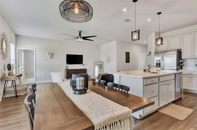 dining area with light hardwood / wood-style floors, sink, and ceiling fan