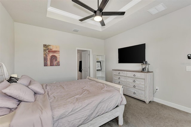 carpeted bedroom with ceiling fan, crown molding, and a tray ceiling