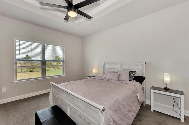 carpeted bedroom with ceiling fan and a tray ceiling