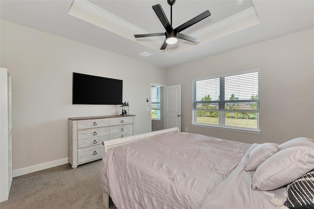 bedroom with ceiling fan, light colored carpet, and a tray ceiling