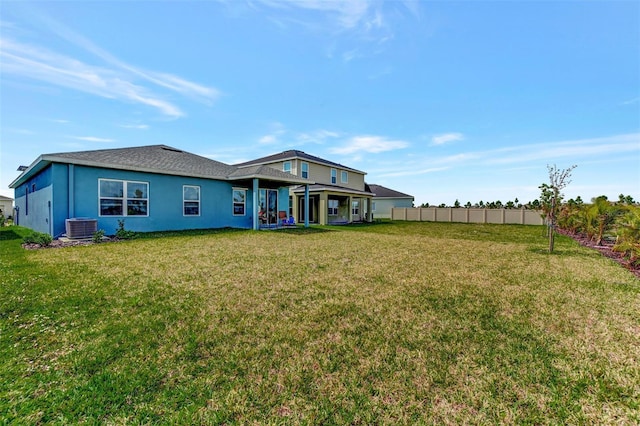 back of property with central AC unit and a yard