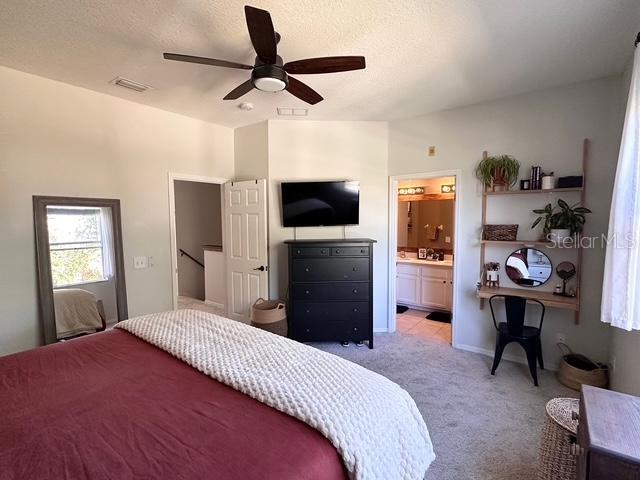 carpeted bedroom featuring ceiling fan and ensuite bathroom