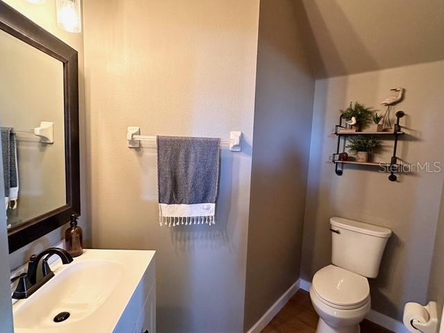 bathroom with lofted ceiling, vanity, and toilet