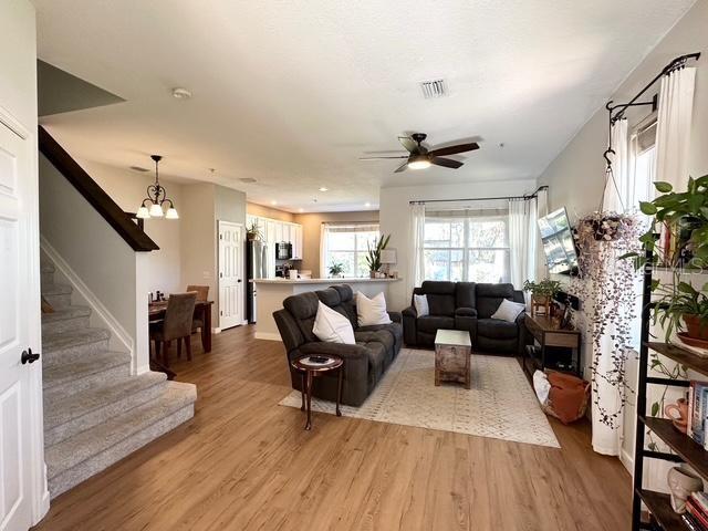 living room with ceiling fan with notable chandelier and light hardwood / wood-style flooring