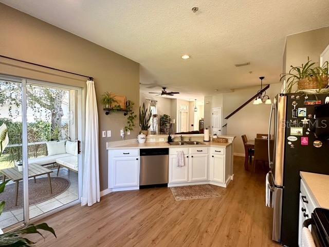 kitchen with light wood-type flooring, sink, stainless steel appliances, and white cabinetry