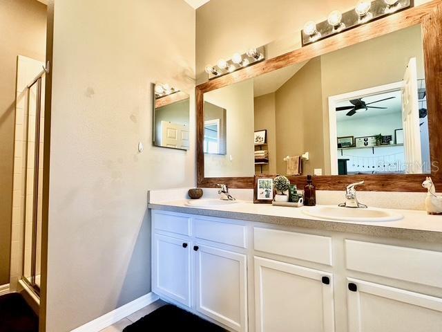 bathroom featuring ceiling fan, vanity, and a shower with door