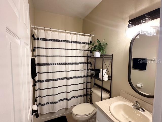 full bathroom with toilet, shower / tub combo, and vanity