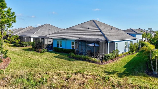 rear view of property featuring glass enclosure and a lawn