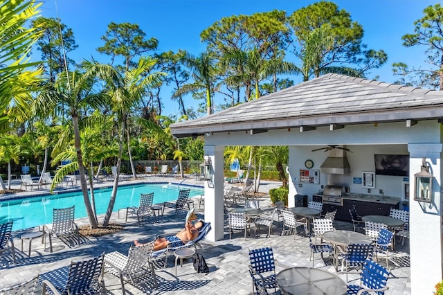 view of pool with ceiling fan, an outdoor kitchen, a patio, area for grilling, and a gazebo