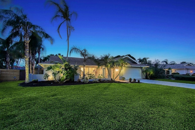 ranch-style house with a garage and a lawn