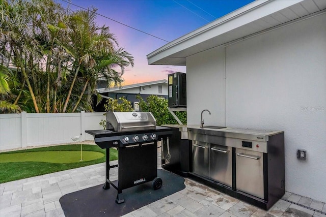 patio terrace at dusk with sink and area for grilling