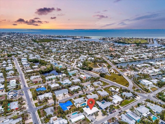 aerial view at dusk featuring a water view