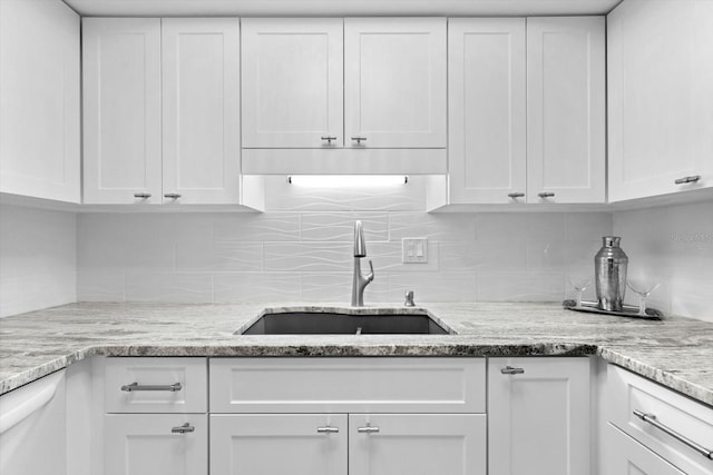 kitchen with white cabinetry, sink, light stone counters, and decorative backsplash