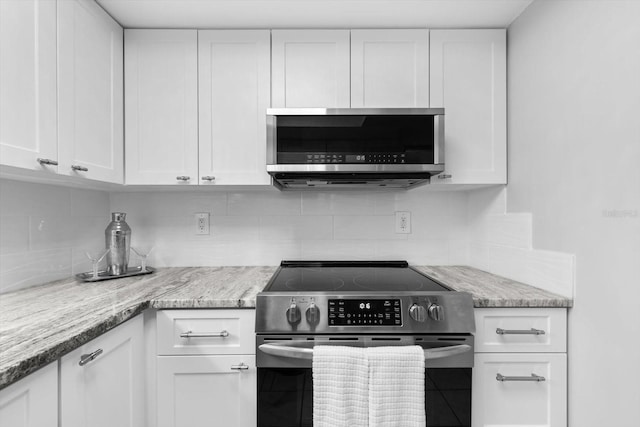 kitchen featuring white cabinetry, appliances with stainless steel finishes, light stone counters, and backsplash