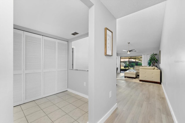 corridor with light hardwood / wood-style flooring and vaulted ceiling