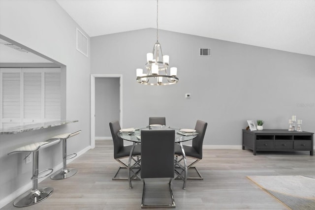 dining area featuring high vaulted ceiling, a chandelier, and light hardwood / wood-style flooring