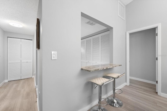 hall featuring light hardwood / wood-style flooring and a textured ceiling