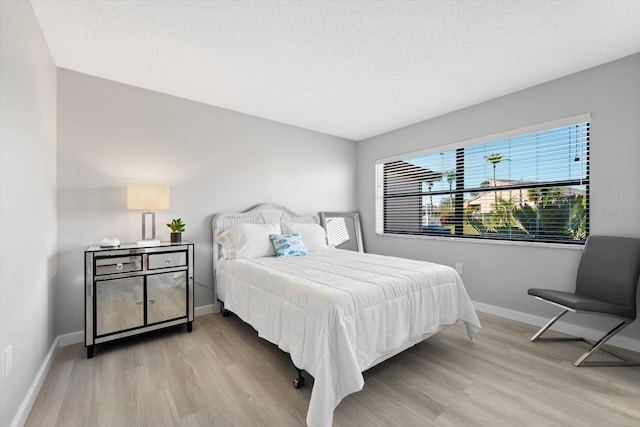 bedroom with a textured ceiling and light hardwood / wood-style flooring