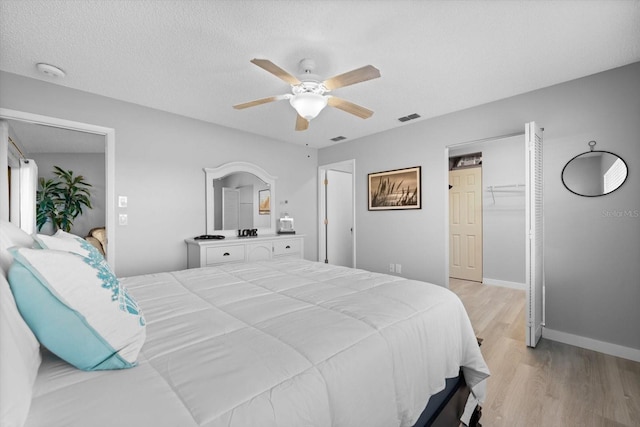 bedroom with ceiling fan, a textured ceiling, and light wood-type flooring