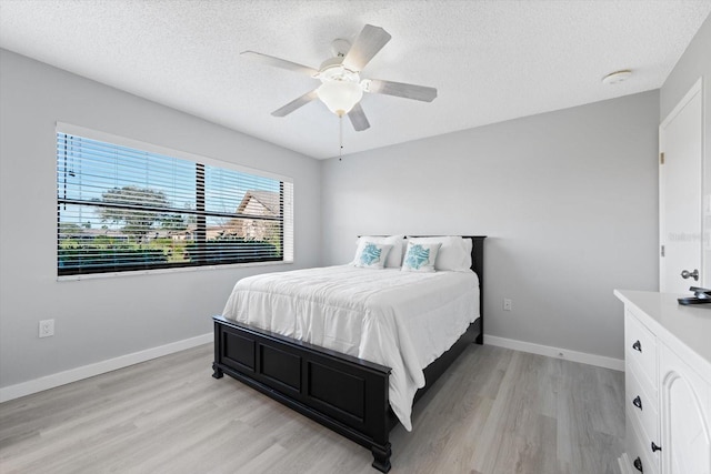 bedroom featuring ceiling fan, light hardwood / wood-style flooring, and a textured ceiling