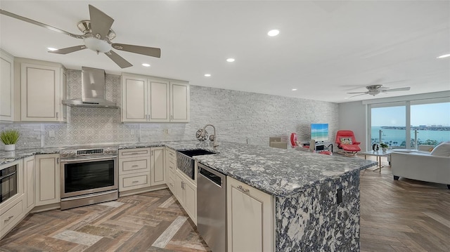 kitchen with sink, dark parquet flooring, kitchen peninsula, stainless steel appliances, and wall chimney range hood