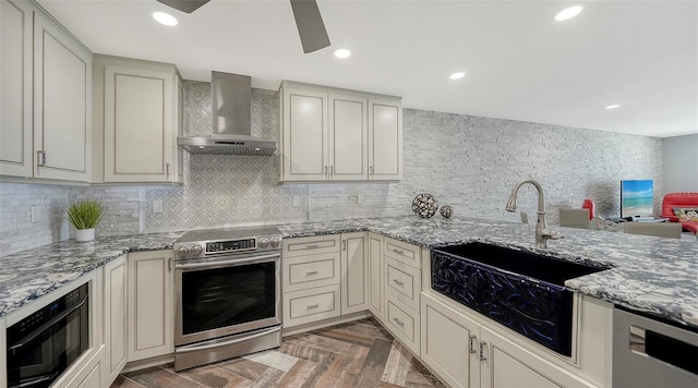 kitchen with stainless steel range with electric cooktop, cream cabinetry, and wall chimney exhaust hood