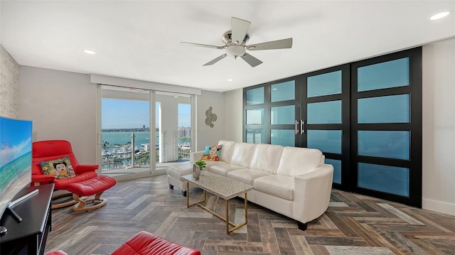 living room featuring a water view, ceiling fan, and dark parquet floors