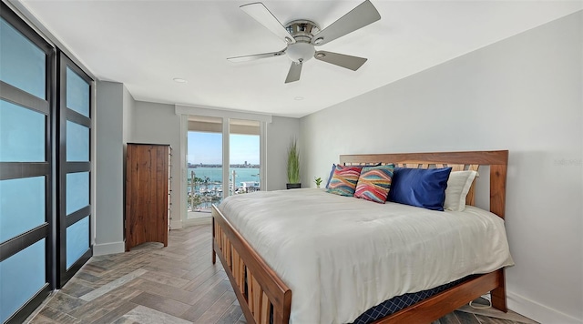 bedroom with a water view, access to exterior, ceiling fan, and parquet flooring