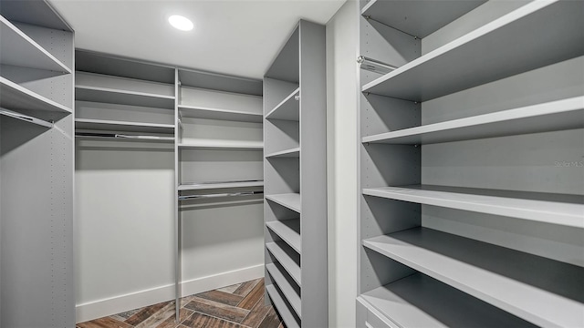 walk in closet with dark parquet flooring