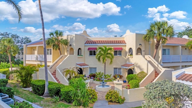 view of front of home featuring stucco siding, a residential view, stairway, and a tiled roof