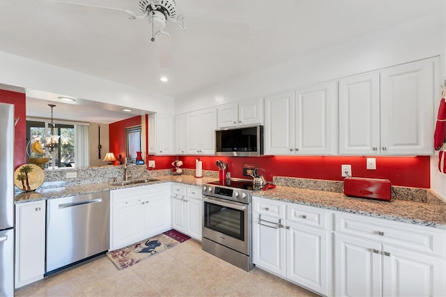 kitchen with stainless steel appliances, a sink, white cabinetry, and light stone countertops