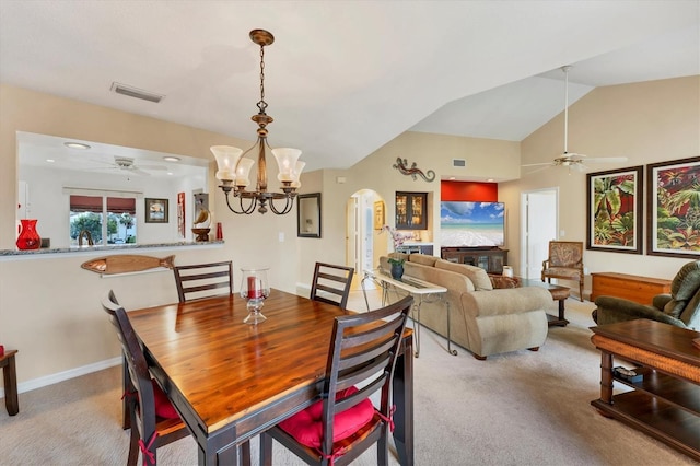 dining space featuring visible vents, arched walkways, lofted ceiling, carpet flooring, and ceiling fan with notable chandelier