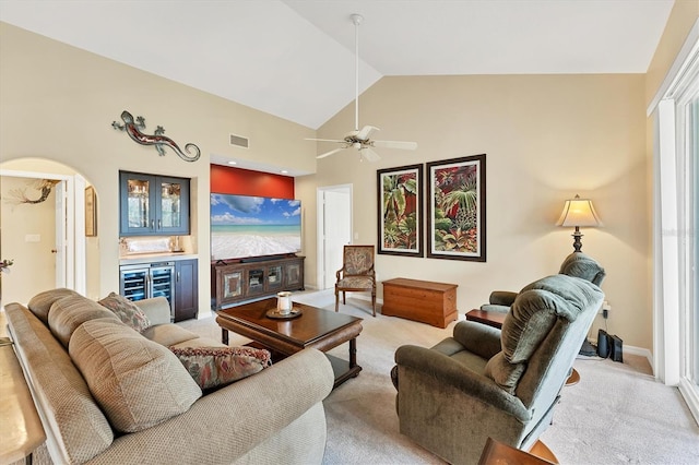 living area featuring arched walkways, light carpet, and a dry bar