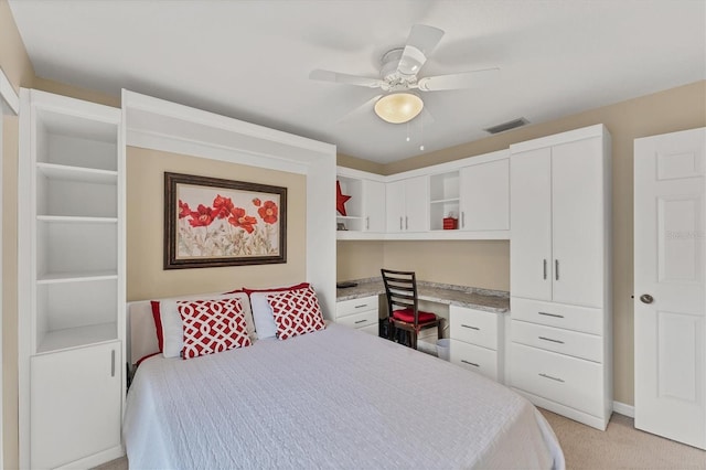 bedroom featuring a ceiling fan, visible vents, built in desk, and light colored carpet