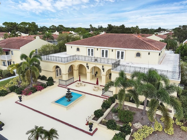 rear view of property with driveway, a tiled roof, fence, french doors, and stucco siding