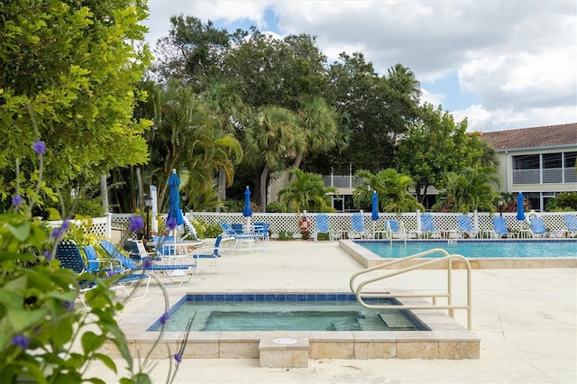 pool featuring a community hot tub, a patio area, and fence