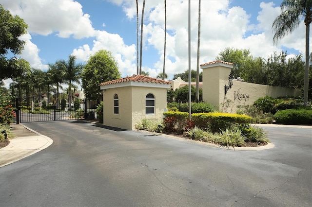 view of road featuring a gate, a gated entry, and curbs