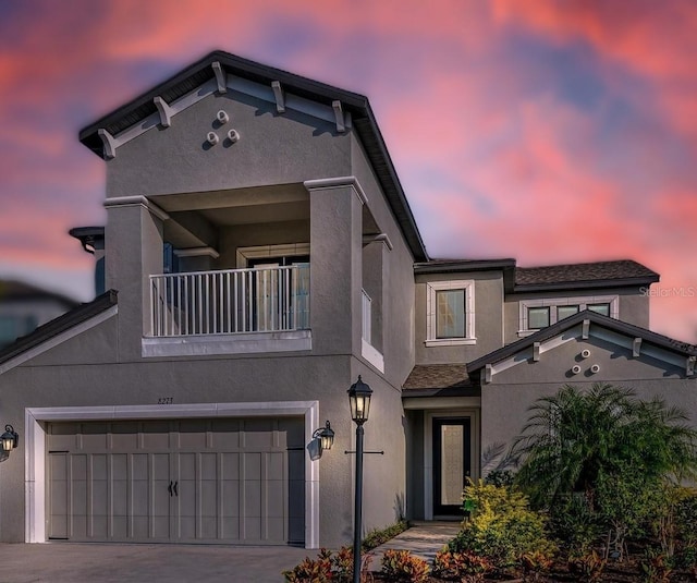 view of front of home featuring a balcony, driveway, a garage, and stucco siding