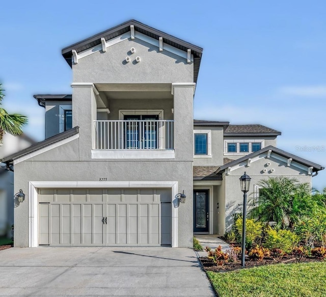 view of front of home featuring a garage, concrete driveway, a balcony, and stucco siding