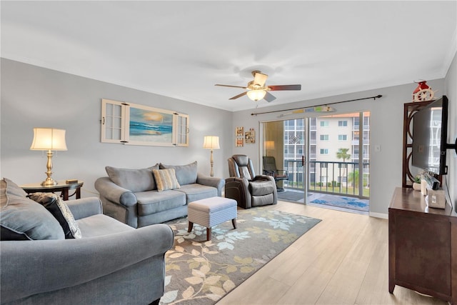 living room featuring ceiling fan, ornamental molding, and light hardwood / wood-style flooring