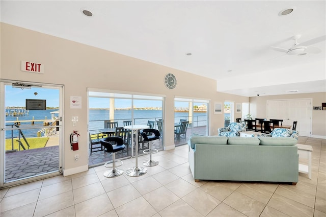 living room featuring light tile patterned floors, ceiling fan, and a water view