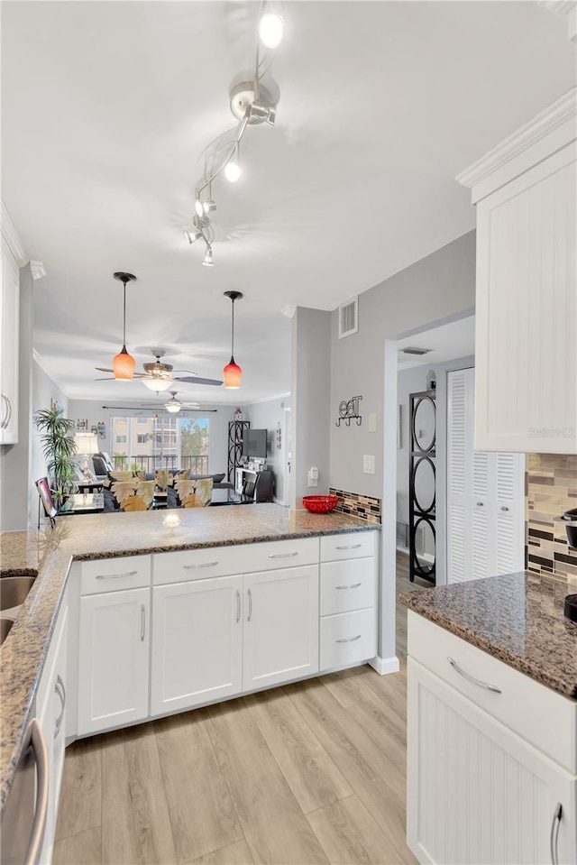 kitchen featuring decorative light fixtures, light hardwood / wood-style flooring, kitchen peninsula, and white cabinets