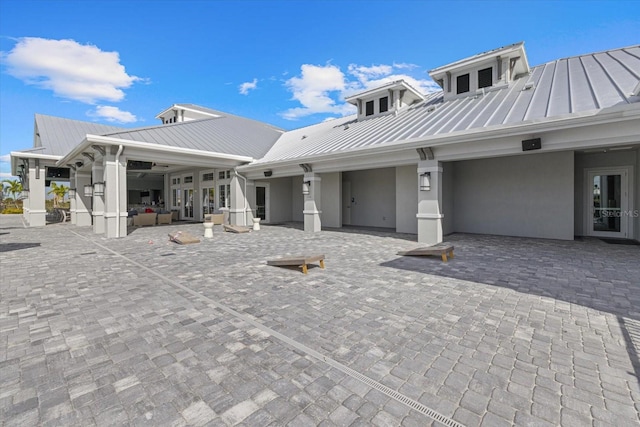 back of property featuring metal roof, a standing seam roof, a patio area, and stucco siding