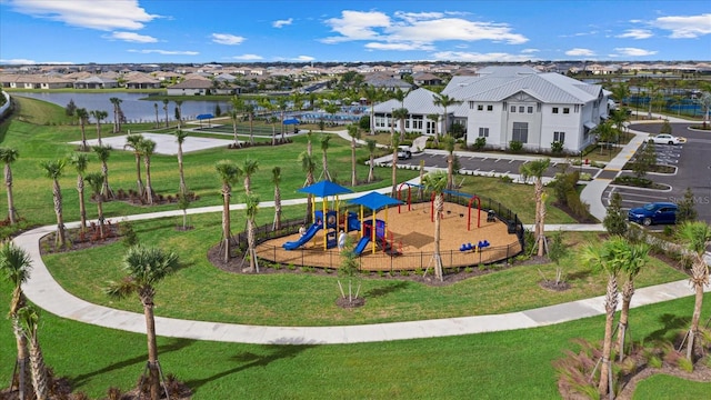 communal playground featuring a water view, a residential view, and a lawn