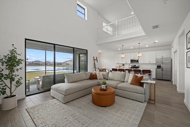 living room featuring light wood-type flooring, a wealth of natural light, a water view, and baseboards